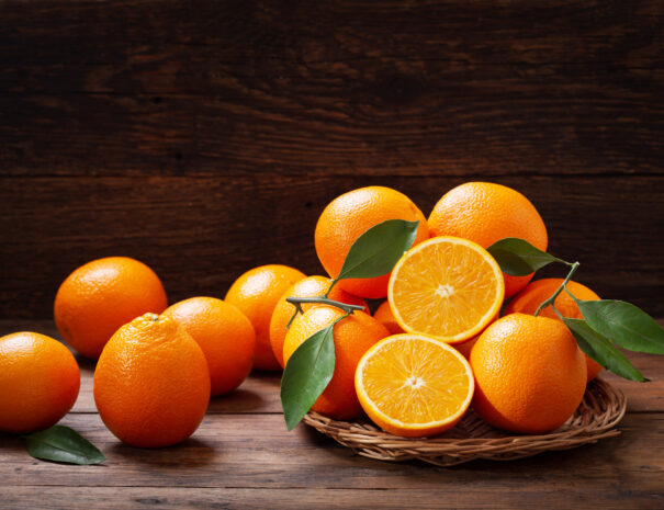 fresh orange fruits with leaves on wooden table